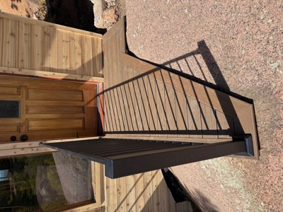 Detail of composite deck boards and black metal railing at a cabin door