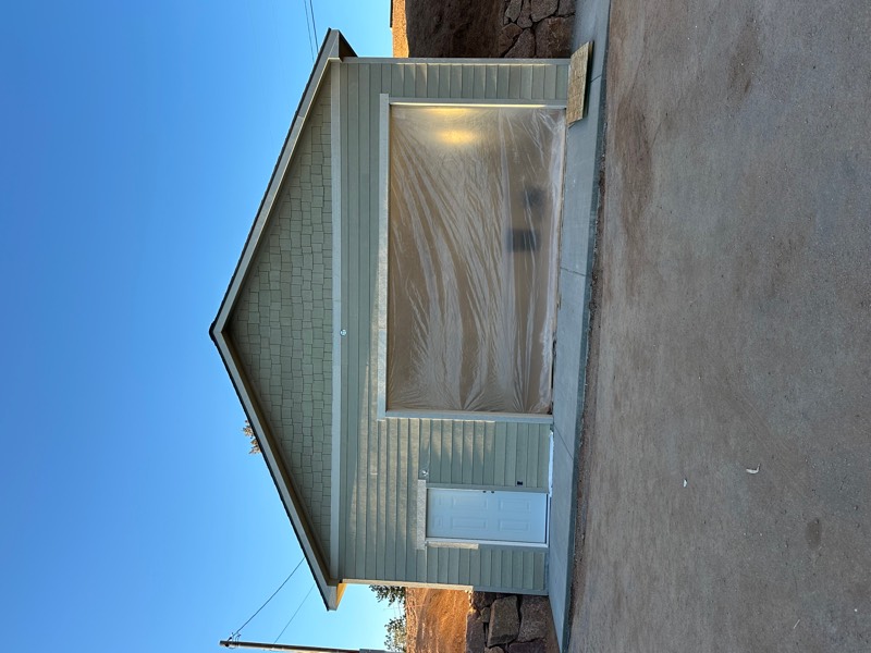 Newly built detached garage with sage green siding and fresh concrete apron