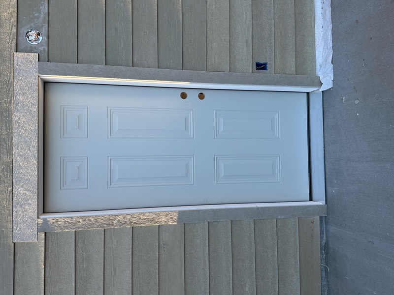 Newly installed white six-panel exterior door with fresh trim